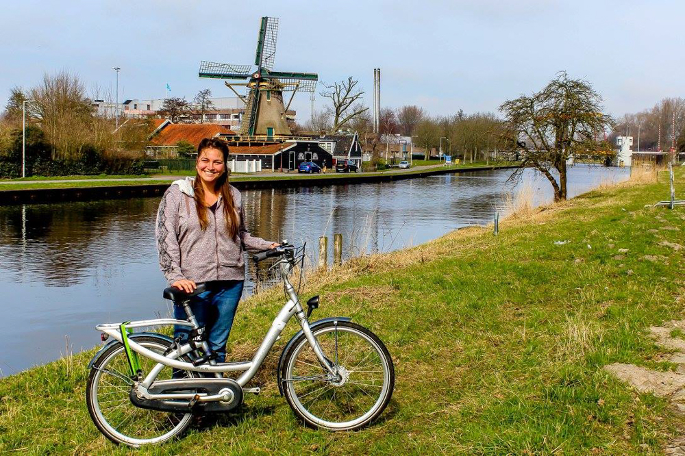 Girl with a bike in front of a windmill in Amsterdam