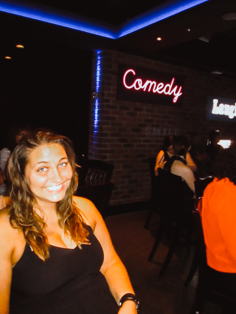 Girl sitting, smiling at a comedy show. 