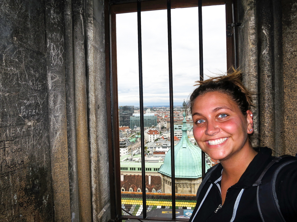 Girl at the top of St. Stephens Cathedral, standing by a window overlooking Vienna