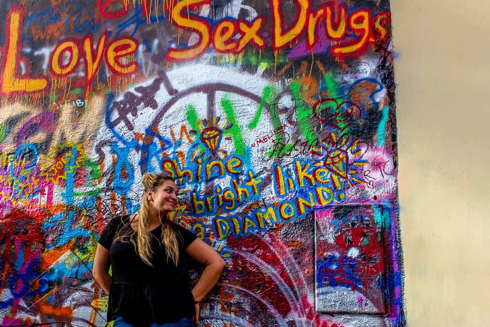 Girl standing in front of Lennon wall in Prague.