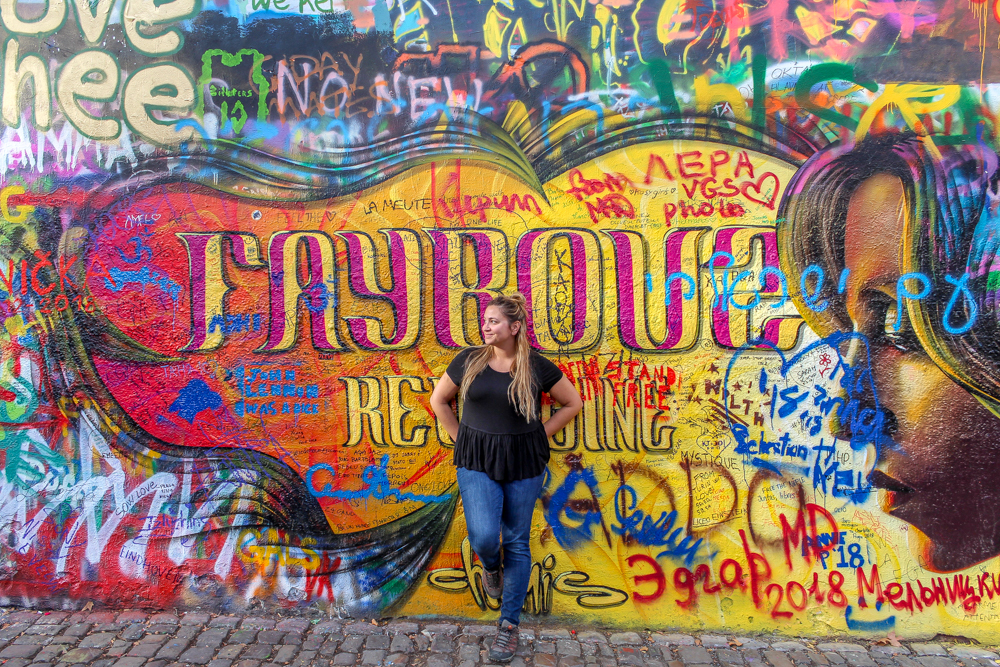 Girl standing in front of Lennon Wall in Prague