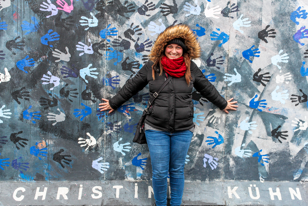 Overweight and traveling  girl in front of Berlin wall